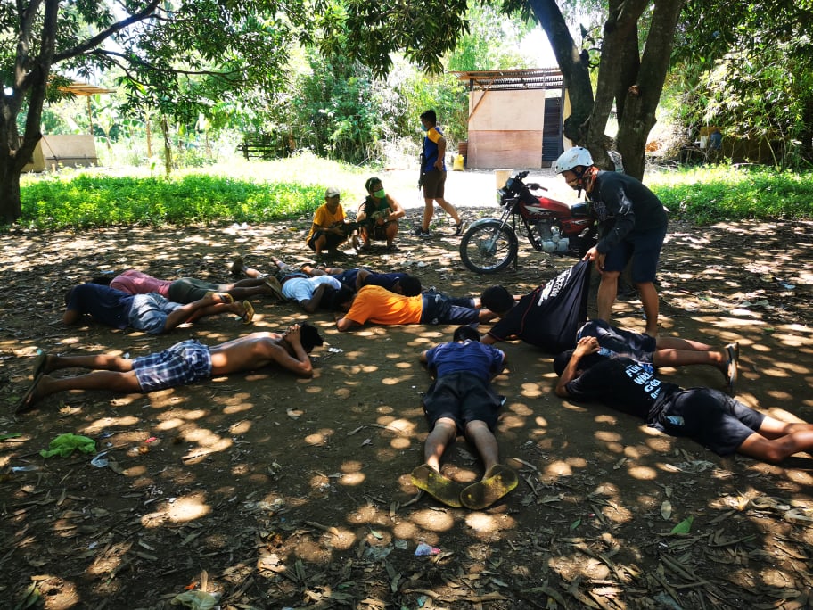 Some of the 13 men caught engaging in tigbakay and hantak are told to lie down on the ground during the raid in Sitio Ipil-Ipil, Barangay Estaca, Compostela, Cebu on Sunday noon, September 13. | Photo from Compostela Police Station
