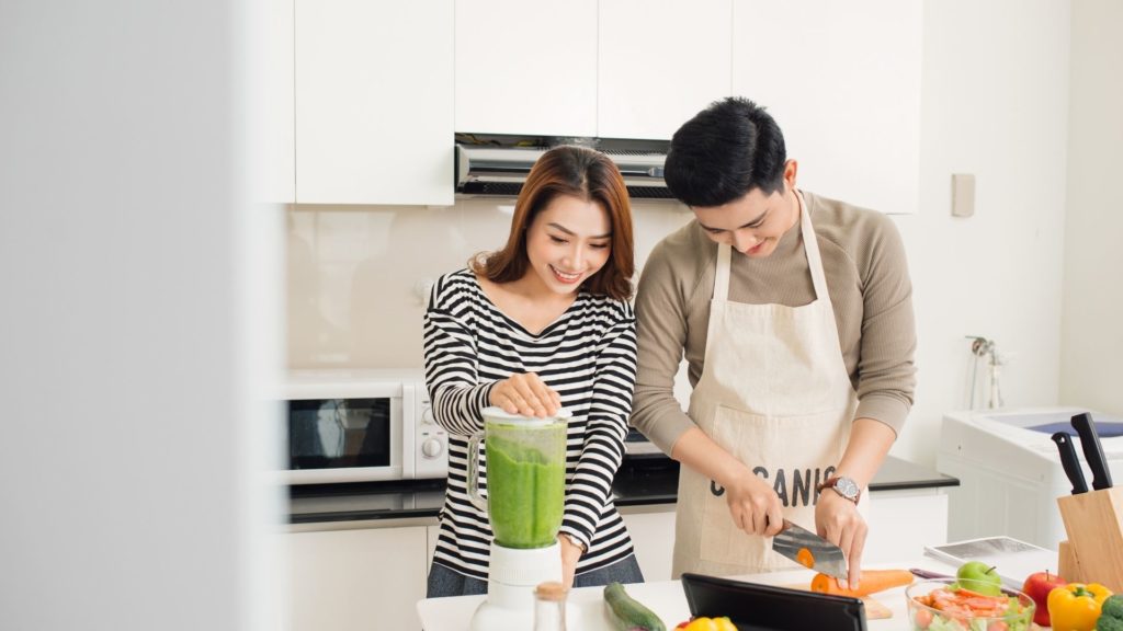 Couple helping each other cook at kitchen 