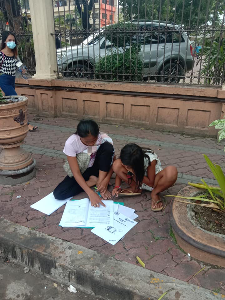 A mother helps her daughter with her learning modules along a sidewalk in a street in Mabini, Cebu City. | Photo courtesy Genevive Bangay