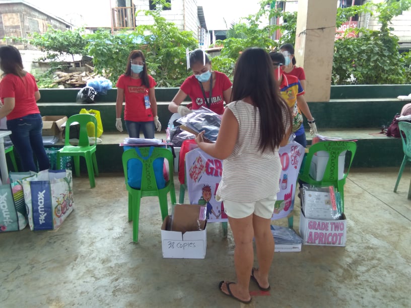 A parent back to camera picks up the distance learning modules from teachers under DepEd Mandaue at the gymnasium in Barangay Paknaan in Mandaue City on Friday, October 9, 2020. | CDN Digital photo by Mary Rose Sagarino