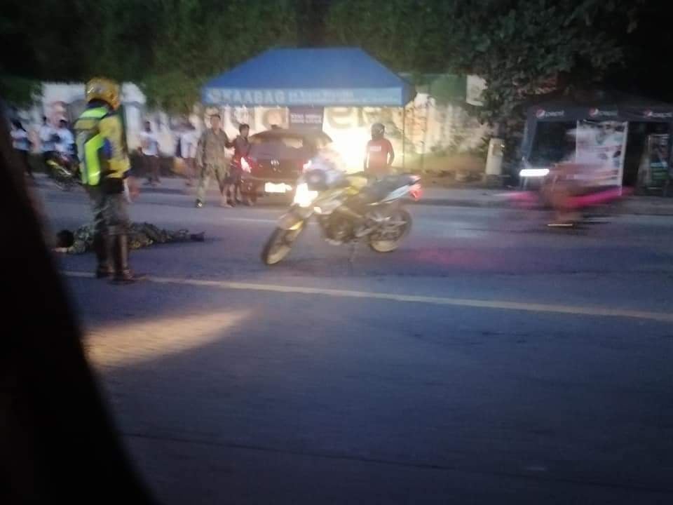 A policewoman lies at the center of the road after she was hit by a car as she manned a quarantine checkpoint at the border of Mandaue City and Consolacion town on the early morning of December 24, 2020. | via Paul Lauro