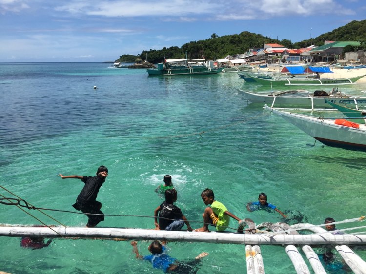 Children play and enjoy a morning swim as they jump from the outrigger of a boat anchored at the island's shore. | Doris Bongcac