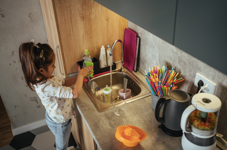 Children can be taught responsibility at an early age so that they will grow up into responsible adults. In photo is a child washing the dishes in the kitchen.