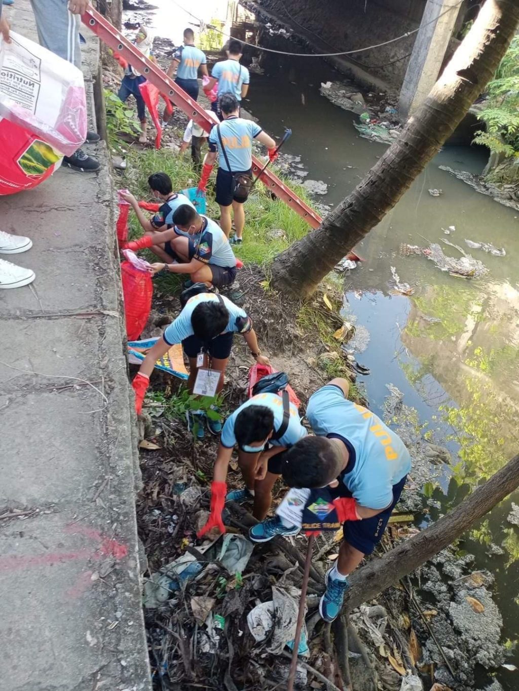 Policemen of the Centro Police Station clean the side of a creek in Barangay Guizo, Mandaue City today, June 18. | Photo courtesy of Police Major Eric Gingoyon