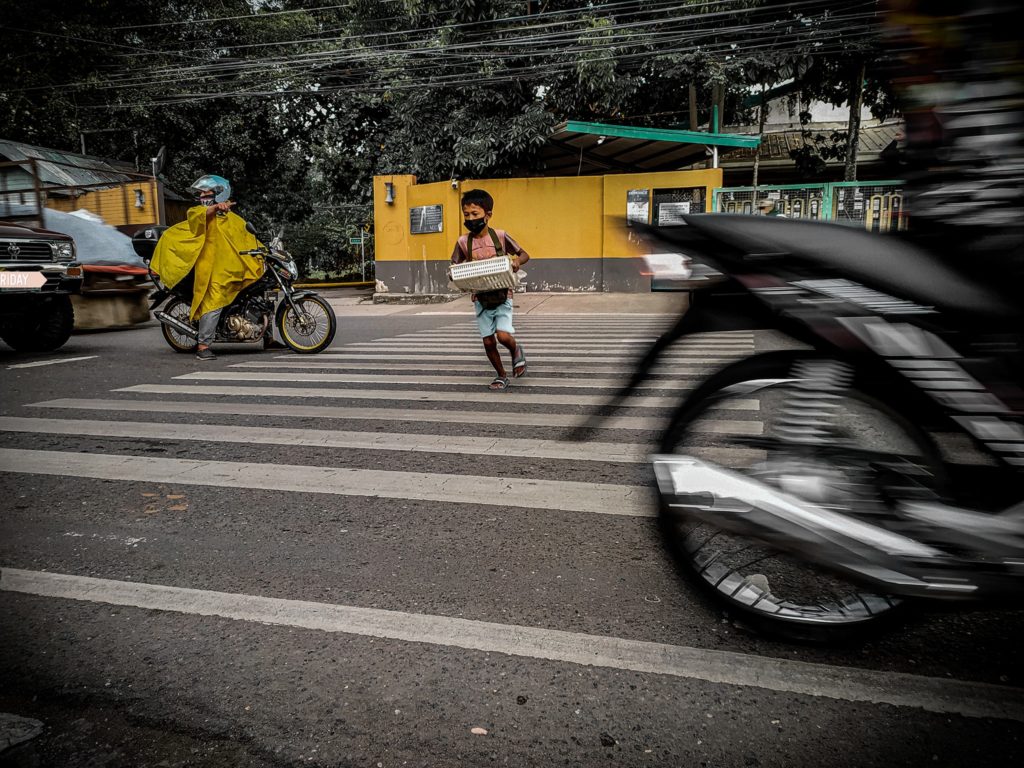 This is the viral photo of a boy crossing the street with a motorist at the back of the motorcycle angrily honking his horn because the motorcycle driver stopped and allowed the child to cross the street.