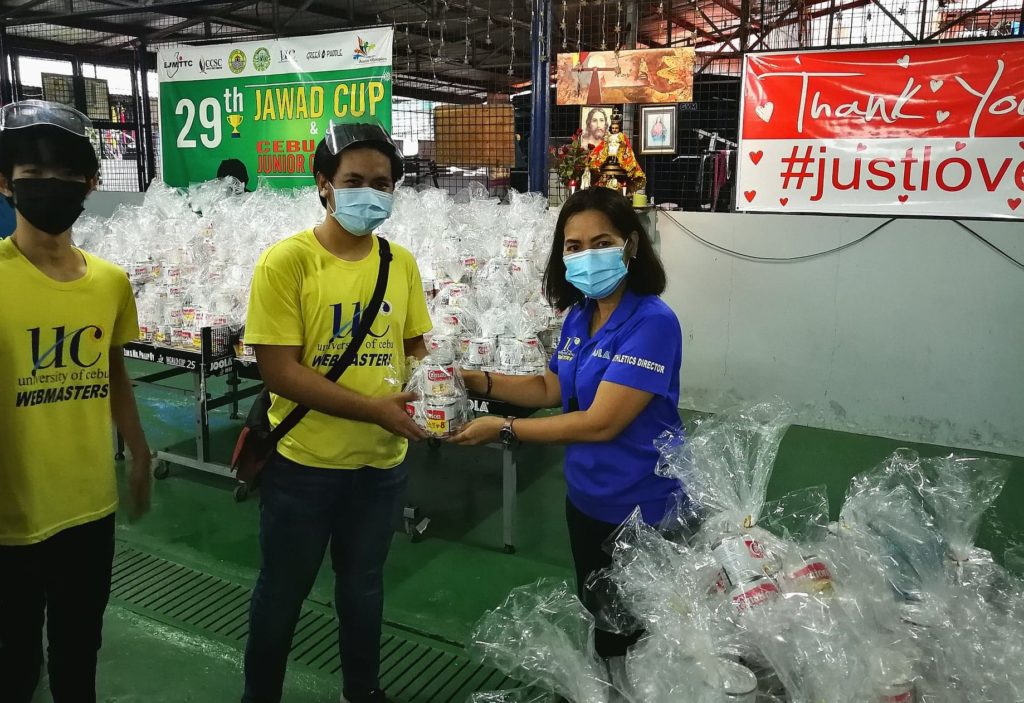 UC athletic director Jessica Honoridez hands out the canned goods to one of her athletes at the UC community pantry at the back of the Cebu Coliseum in downtown, Cebu City on Saturday, Sept 25. | Photo by Glendale Rosal