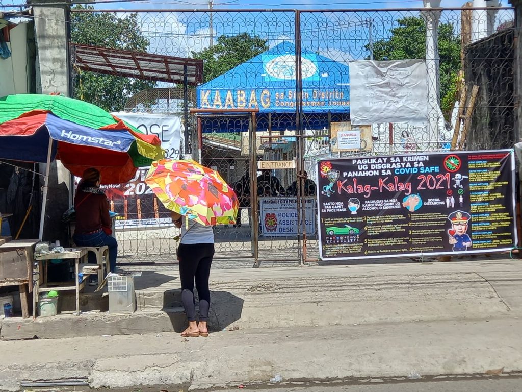 Kin of a departed loved one inside the Mandaue cemetery offer prayers, light candles in front of the closed gate of the cemetery. | Mary Rose Sagarino