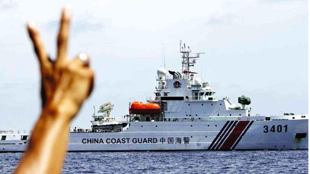 A Philippine Marine soldier flashes the peace sign to a Chinese Coast Guard ship after it tried to block a resupply vessel from restocking the BRP Sierra Madre on Ayungin Shoal in 2014. INQUIRER FILE PHOTO