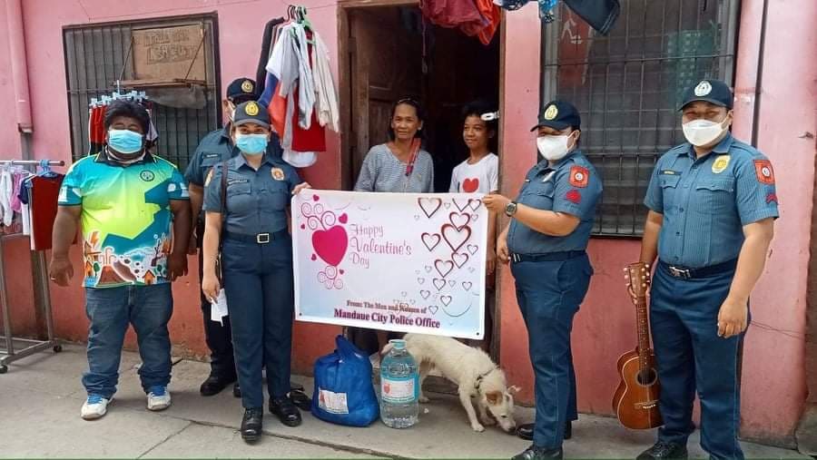 The Mandaue police give relief goods and a 10 liter bottle of water to victims of Odette, who lost loved ones in Sitio Sudlon, Barangay Maguikay, Mandaue City today, Valentine's Day. | Mary Rose Sagarino