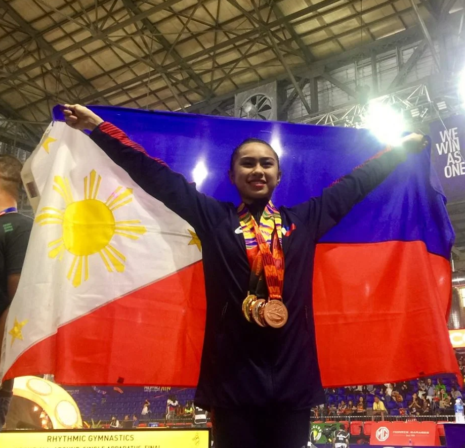 Daniela Reggie Dela Pisa raises the Philippine flag during the awarding ceremony of the women's rhythmic gymnastics in the 2019 SEA Games. | CDN File Photo