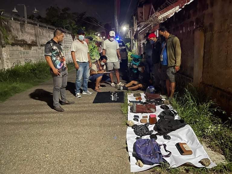 BASAG KOTSE THIEF NABBED. Police check on the recovered items made up of several bags and wallets from suspect Allan Perales, who was allegedly a Bukas Kotse thief. | Contributed photo via Pegeen Maisie Sararaña
