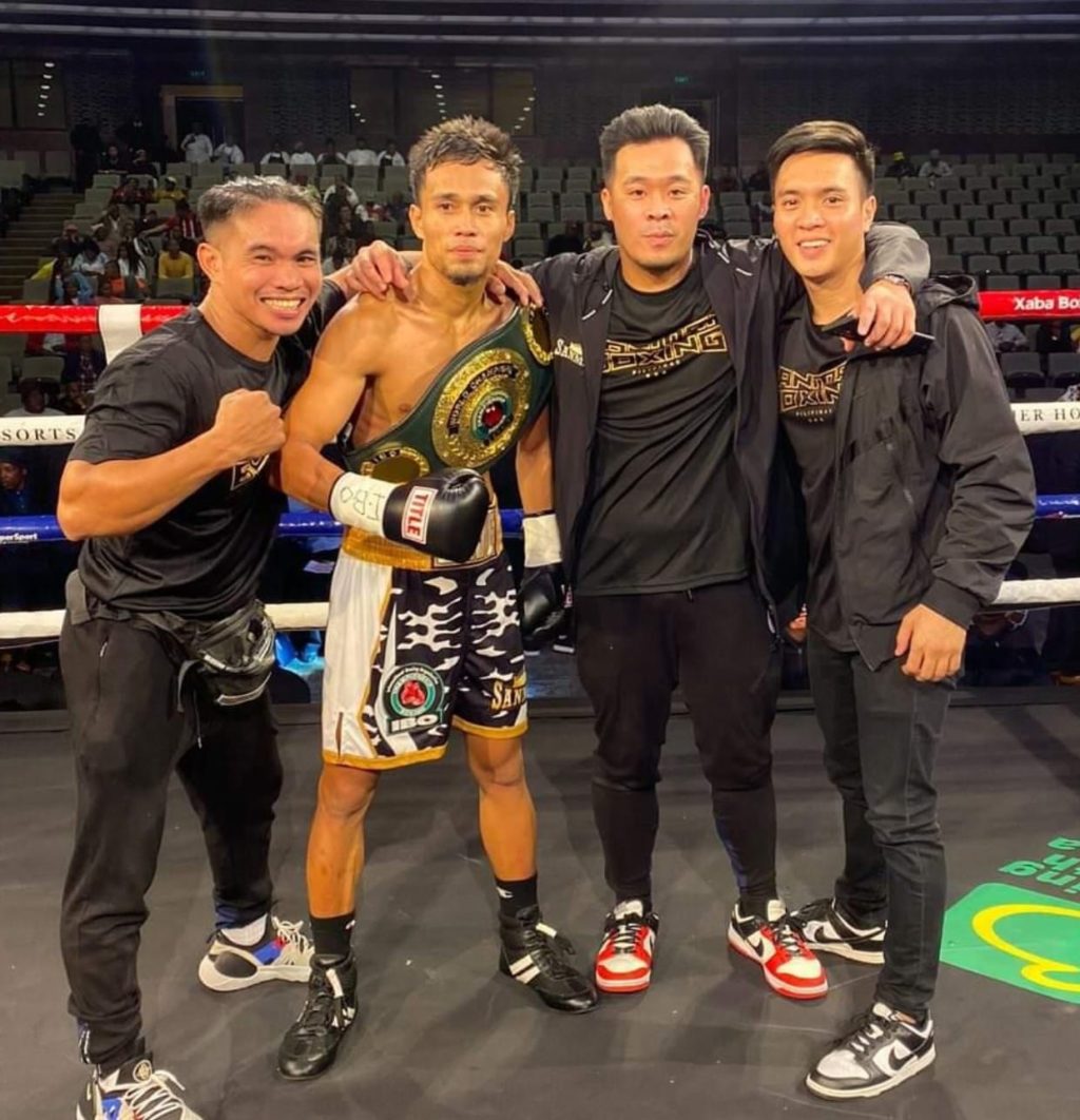 Dave Apolinario, who is wearing the IBO world flyweight title on his shoulders, is surrounded by his team. | Photo from Sanman Boxing Facebook page