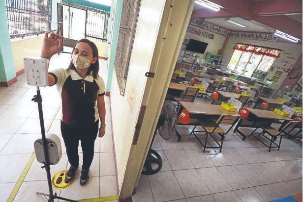 (FILE PHOTO) On October 19, 2021, a grade school teacher of Aurora Quezon Elementary school in Manila demonstrate what a face-to-face class would look like amid the COVID-19 pandemic, with plastic barriers separating each armchair from one another and teachers wearing PPE during class. INQUIRER/MARIANNE BERMUDEZ