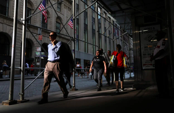People walk on Wall St. during the morning commute, as the city deals with record temperatures and the excessive heat, in New York City, U.S., July 20, 2022. REUTERS