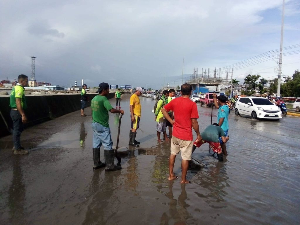 Talisay City workers declog the canals near the flooded roads in the city.