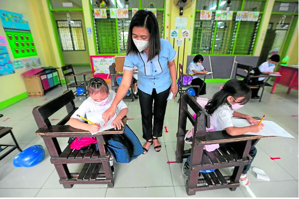 (FILE) A teacher points at something to a student at Pedro Cruz Elementary School in San Juan City as it reopened on Feb. 10, 2022 (Photo by GRIG C. MONTEGRANDE / Philippine Daily Inquirer)