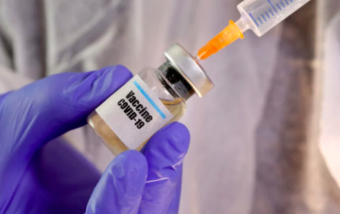 FILE PHOTO: A woman holds a small bottle labeled with a “Vaccine COVID-19” sticker and a medical syringe in this illustration taken April 10, 2020. REUTERS/Dado Ruvic