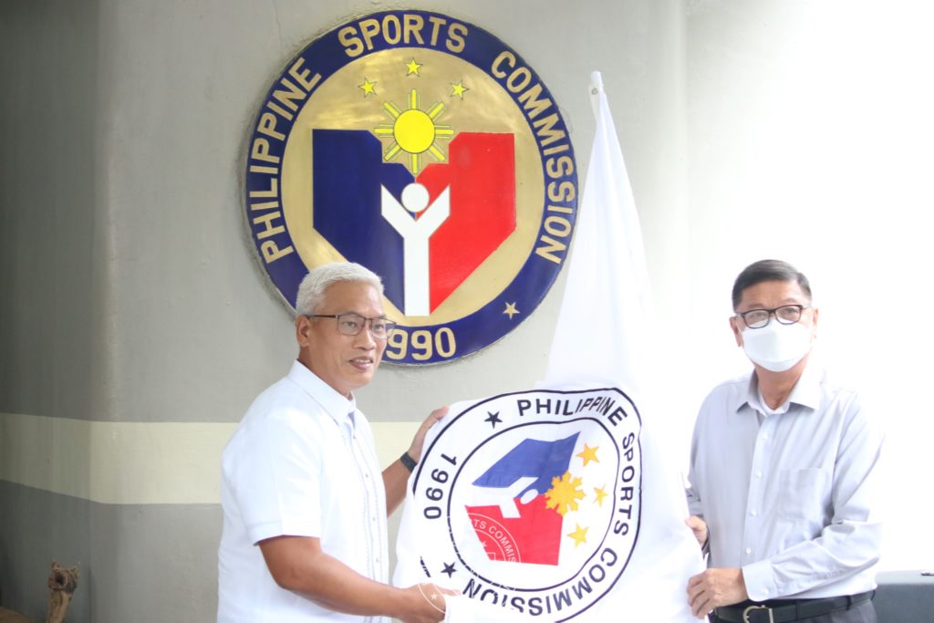 Newly appointed PSC Chairman Noli Eala and outgoing PSC Chairman William "Butch" Ramirez hold the PSC flag during Monday's turnover ceremony. | Photo from the PSC