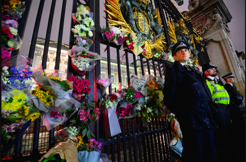 Police officers stand guard as flowers are laid at a gate of Buckingham Palace after Queen Elizabeth, Britain’s longest-reigning monarch and the nation’s figurehead for seven decades, died aged 96, in London, Britain September 8, 2022. REUTERS/Toby Melville