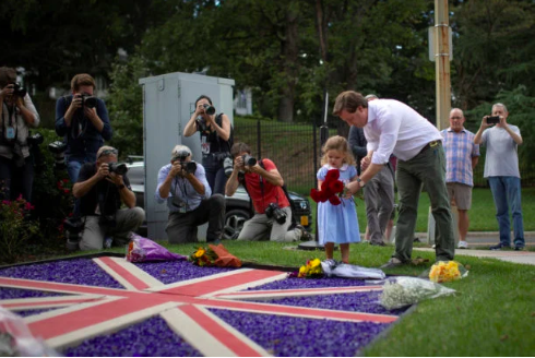 Edward Rodgers helps his daughter, India, lay flowers following the announcement of the death of Queen Elizabeth, at the British Embassy in Washington, U.S., September 8, 2022. (REUTERS)