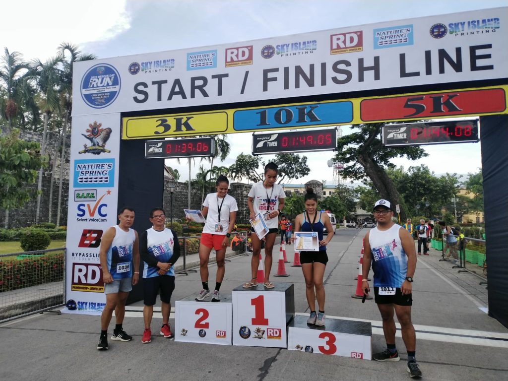 Art Joy Torregosa (top of the podium) joins fellow winners in the distaff side of the 10K Heroes Day Fun Run. The other winners are Reinhardt Pañibon (2) and April Cortes (3). | Contributed Photo