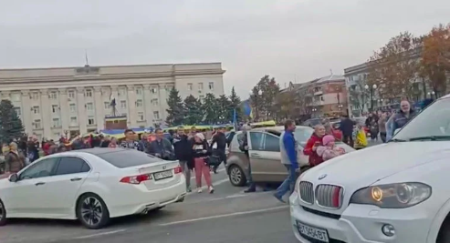 Crowd cheer and chant as they surround a car with Ukrainian soldiers in Kherson Freedom Square, Ukraine in this screen grab obtained from a video released on November 11, 2022. (Video obtained by Reuters/Handout via REUTERS)