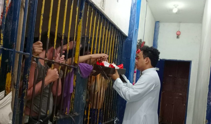 Iñaque Shaquille Garlet, altar server and staff at the Cultural and Historical Affairs Office and president of the Ministry of the Altar Servers at the Archdiocesan Shrine of San Nicolas de Tolentino Parish, gives inmates a chance to touch and send prayers to the image of the newborn Jesus at the San Nicolas Police Station detention cell on Christmas Day, Dec. 25. | Contributed photo