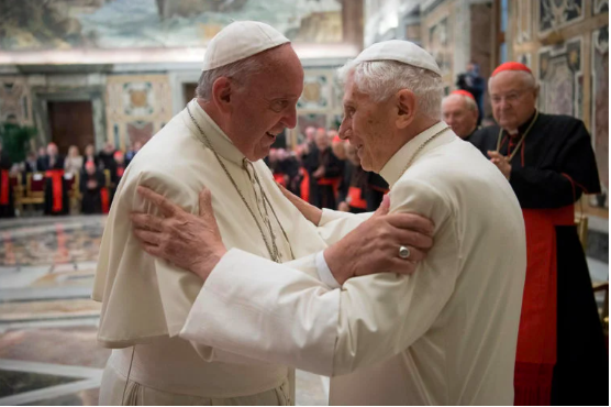 FILE PHOTO: Former pope Benedict (R) is greeted by Pope Francis during a ceremony to mark his 65th anniversary of ordination to the priesthood at the Vatican June 28, 2016. Osservatore Romano/Handout via Reuters