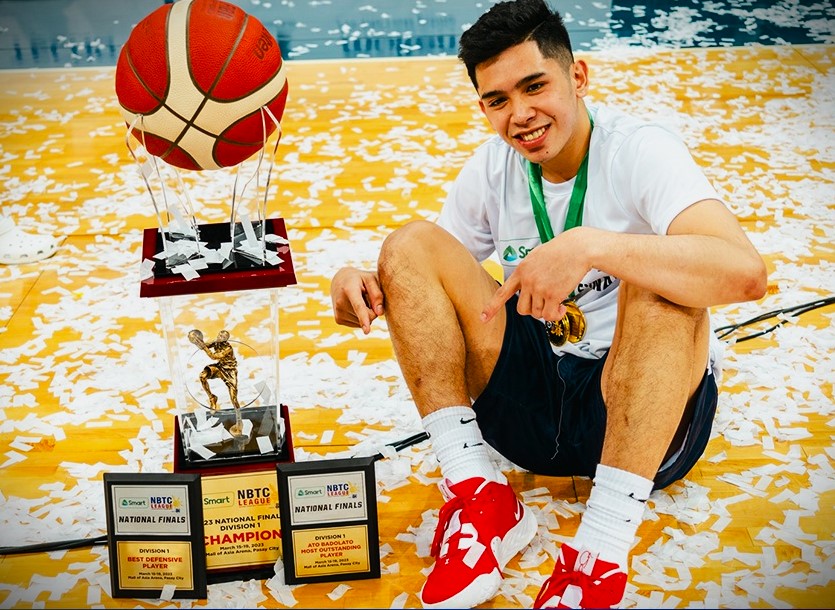 Reinhard Jumamoy sits beside the NBTC National Finals champion's trophy and his two individual awards. 