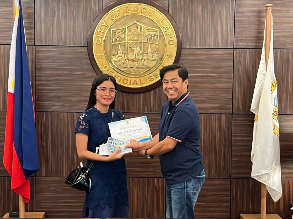Topnotcher, 149 others receive cash incentives. In photo is a board passer receiving her P5,000 cash incentive from Lapu-Lapu City Mayor Junard "Ahong" Chan. | Contributed photo