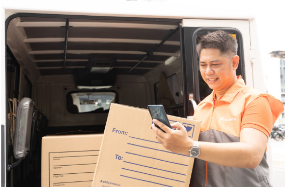 Lalamove truck owner and partner driver checks mobile phone while preparing boxes and packages for delivery