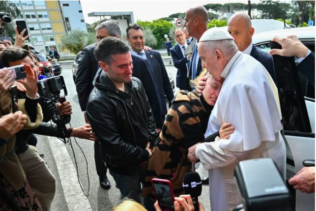 Pope Francis hugs Serena Subania as her husband Matteo Rugghia (L) reacts, a couple who lost their five-year-old child a day earlier, as the Pope leaves the Gemelli hospital on April 1, 2023 in Rome, after being discharged following treatment for bronchitis. The 86-year-old pontiff was admitted to Gemelli hospital on March 29, 2023 after suffering from breathing difficulties. (Photo by Filippo MONTEFORTE / AFP)