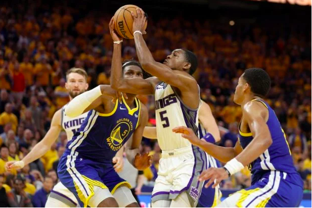 De’Aaron Fox #5 of the Sacramento Kings drives on Kevon Looney #5 and Stephen Curry #30 of the Golden State Warriors in the second half of Game Six of the Western Conference First Round Playoffs at Chase Center on April 28, 2023 in San Francisco, California. Ezra Shaw/Getty Images/AFP