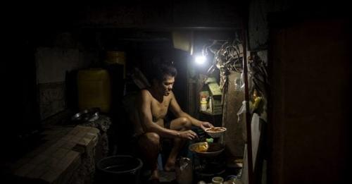A man, who lives in a shanty, prepares dinner for his family in this file photo.