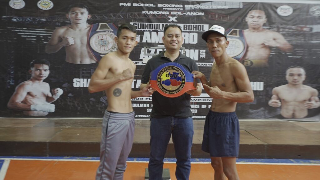 Jake Amparo (left) and Clyde Azarcon (right) flank PMI Bohol Boxing Promotions manager and promoter Floriezyl Podot who is holding the Philippine minimumweight title during the official weigh-in of Kumong Bol-Anon 10. | Photo from PMI Bohol Boxing Stable