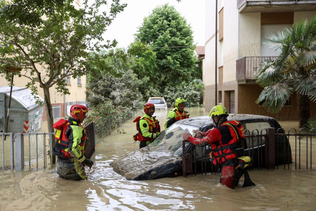 Firefighters work next to a flooded car, after heavy rains hit Italy's Emilia Romagna region, in Faenza, Italy, May 18. REUTERS/Claudia Greco