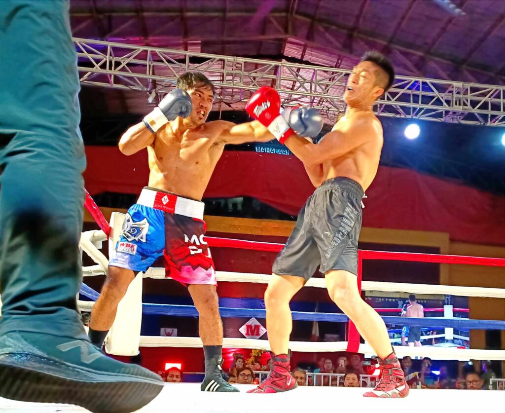 Elmo Traya (in red/blue trunks) threw a jab to Chinese WeiWei Liu (black trunks) during their WBF Australasian super lightweight title bout in Consolacion town, north Cebu Saturday night.