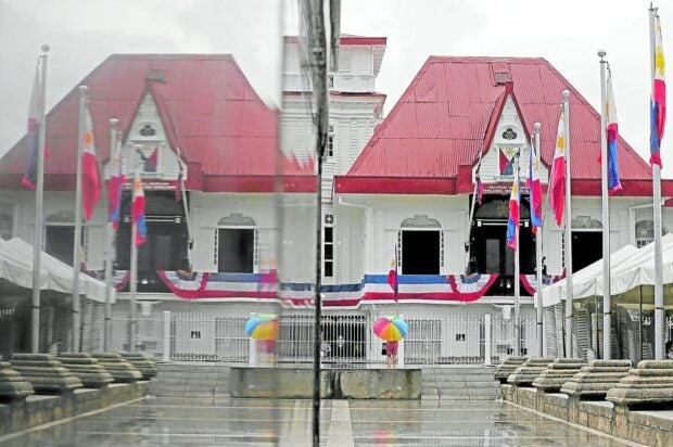 The row, rebrandings behind Independence Day. LOOKING BACK | In the rainy weather, a woman visits the Aguinaldo Shrine on the eve of Independence Day, its facade also reflected on the pedestal of President Emilio Aguinaldo’s statue fronting his home. (Photo by RICHARD A. REYES / Philippine Daily Inquirer)