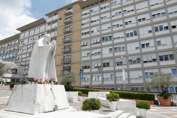 Flowers are seen at the statue of Pope John Paul II at Gemelli Hospital where Pope Francis is hospitalized for surgery on his abdomen, in Rome, Italy, June 10, 2023. REUTERS