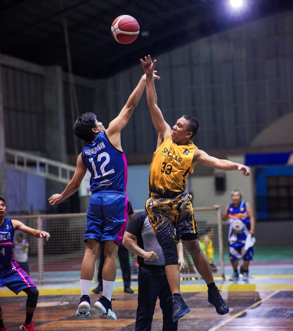 Chester Hinagdanan (12) and Ronaldo Fabian battle for ball possession in mid-air during the tip-off of their quarterfinals match in the Architects + Engineeers Basketball's 6th Corporate Cup.