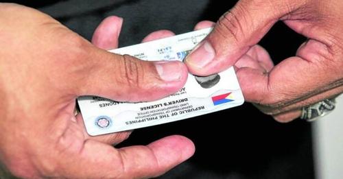 Photo of a man holding a sample of LTO's new driver's license card.