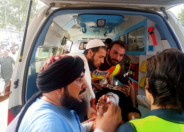 In this photo provided by Rescue 1122 Head Quarters, rescue workers carry a wounded man after a bomb explosion in the Bajur district of Khyber Pakhtunkhwa, Pakistan, Sunday, July 30, 2023 (Rescue 1122 Head Quarters via AP)