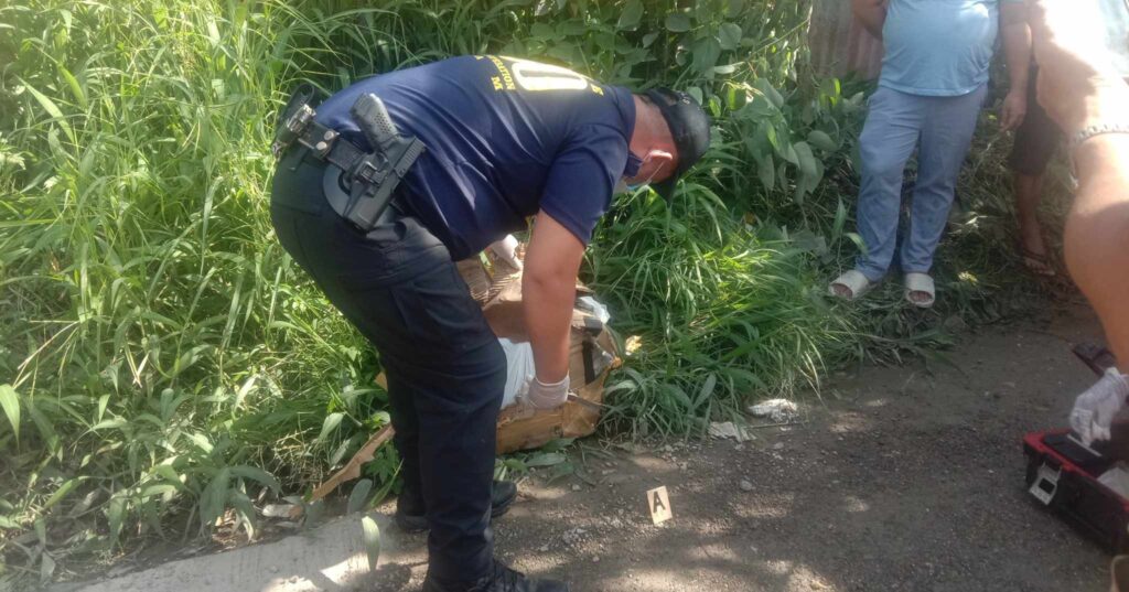 As a crowd gather at the site where a body of a dead person was found inside a box at the side of the road in Barangay Tisa, Cebu City, police start to check and open the box, and a foul smell from the box caused the crowd to cover their noses. | Paul Lauro