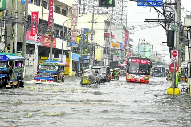 DAGUPAN NAVIGATION | A combination of high tide and heavy rains brought about by Typhoon “Egay” resulted in this situation in one of Dagupan City’s commercial areas on Saturday. A total of 31 barangays in the city were flooded and at least 245 families were forced to evacuate, officials said. (Photo by WILLIE LOMIBAO / Inquirer Northern Luzon)