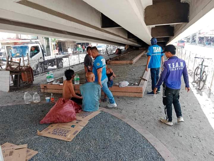 TEAM personnel ask a group of men to vacate the vacant space located below the Maguikay flyover in Mandaue City in this photo taken on Wednesday, August 9, 2023.