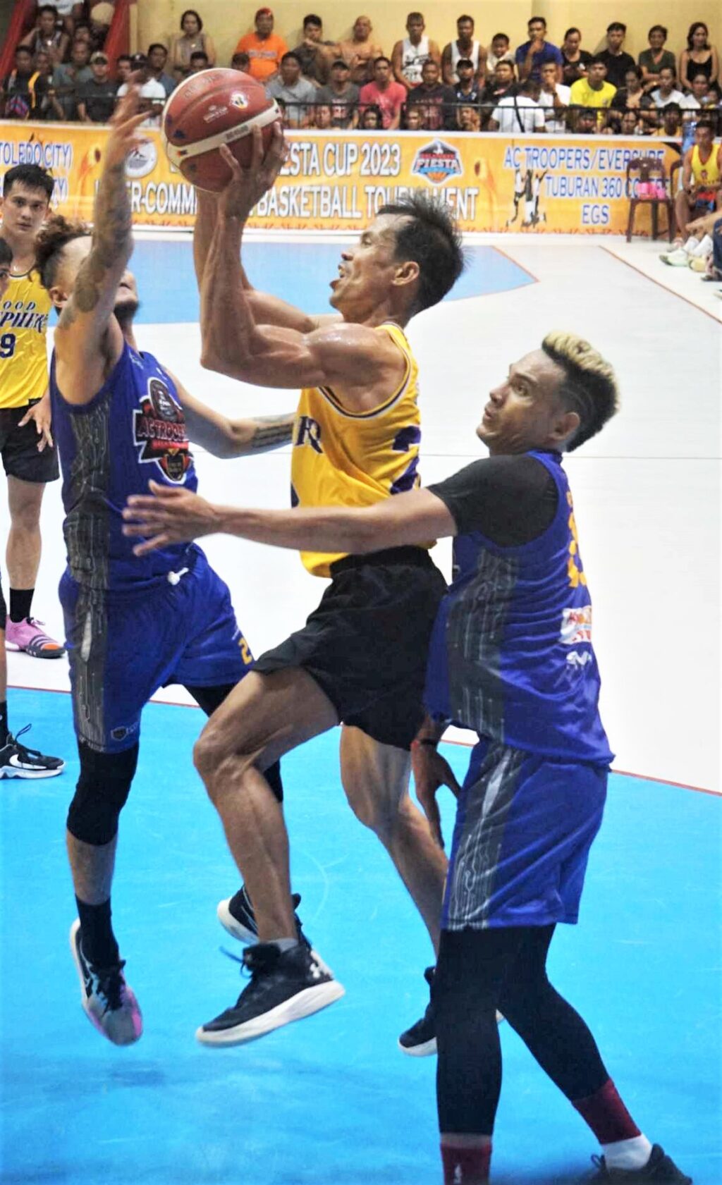 Jojo Tangkay of Good Shepherd-Toledo attempts a difficult shot while being heavily defended by players from AC Troopers/Eversure Catmon during their game in the 2023 Balamban Fiesta Cup Inter-commercial league.