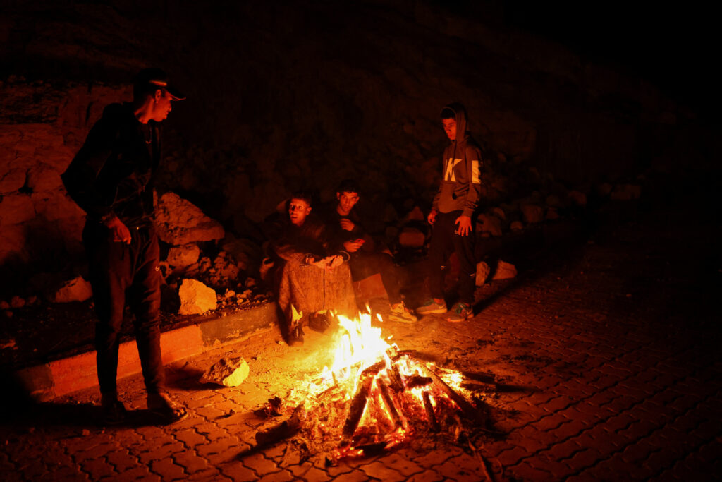 In photo are people sitting around a bonfire in Moulay Brahim Village in the province of Al Haouz, after a powerful earthquake hit this country on September 9.