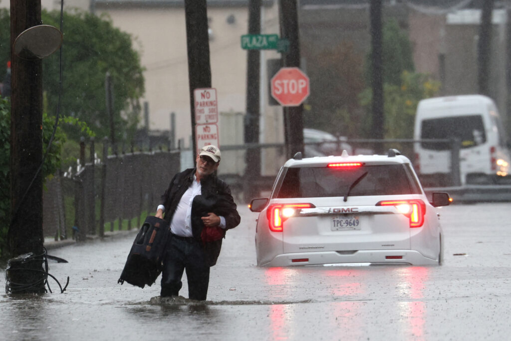A man carries his belongings as he abandons his vehicle which stalled in floodwaters during a heavy rain storm in the NY City suburb of Mamaroneck in Westchester County. September 29, 2023. REUTERS/Mike Segar
