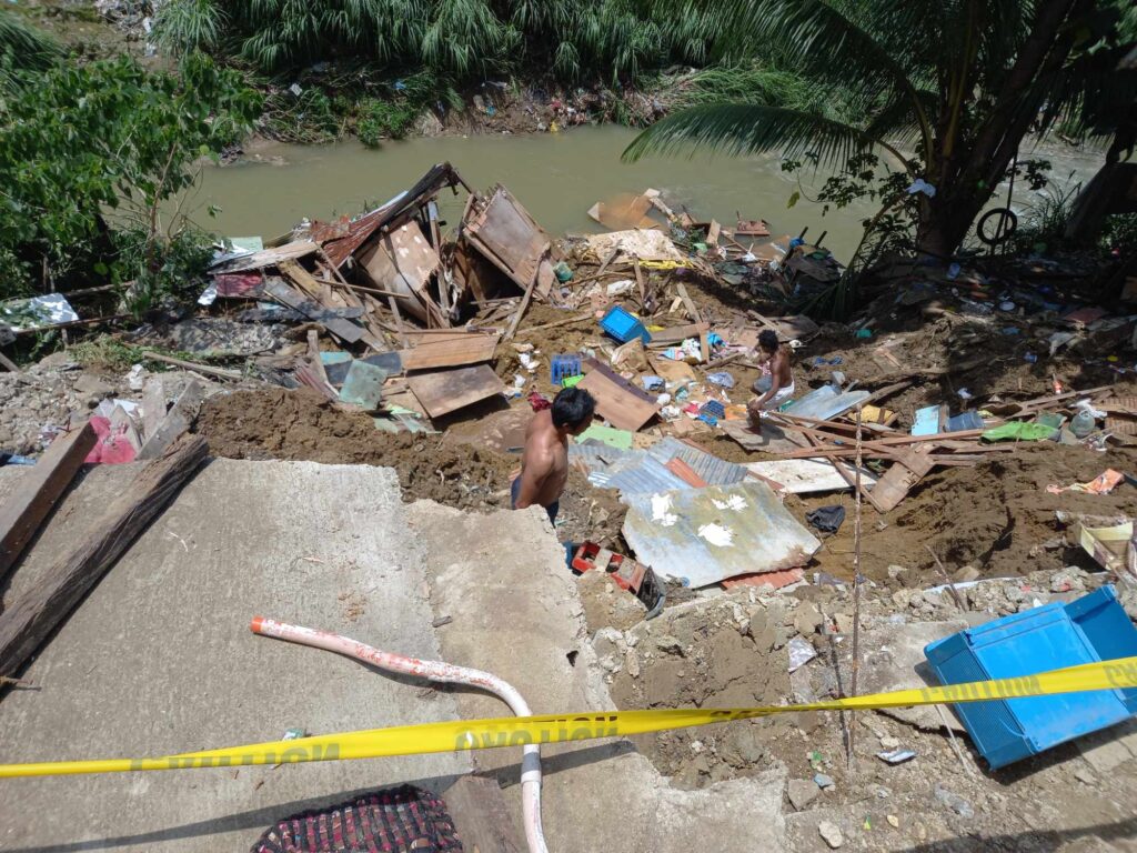 Girl, playing in the rain, dies after she fell into a canal, got swept inside a culvert in Mandaue. In photo is a man is picking things from his house, that can still be used, after his house was damaged by a landslide on Friday afternoon. | Mary Rose Sagarino