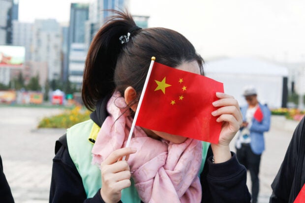 A woman cover her face with a Chinese flag ahead of Pope Francis’s welcome ceremony with President Ukhnaagiin Khurelsukh at Sukhbaatar Square, during his Apostolic Journey in Ulaanbaatar, Mongolia September 2, 2023. REUTERS
